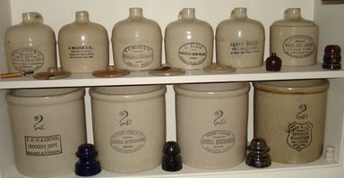 Multiple Red Wing Stoneware Advertising pieces on a shelf